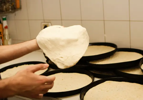 בצק שנפתח ביד מעל מגשי אפייה